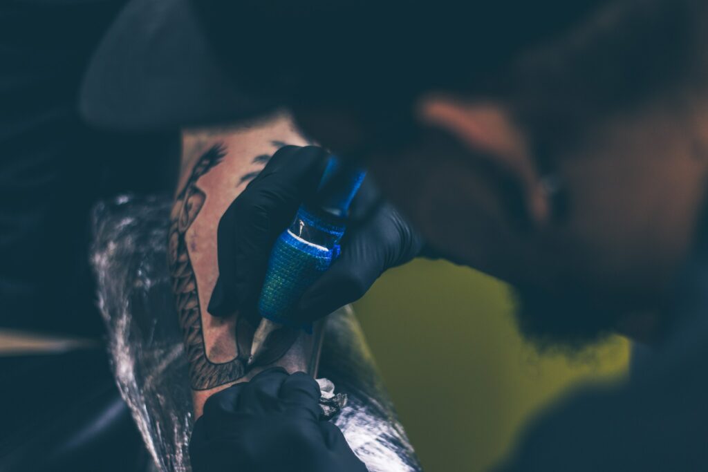 A skilled tattoo artist using a tattoo machine to create a design on a client's arm.